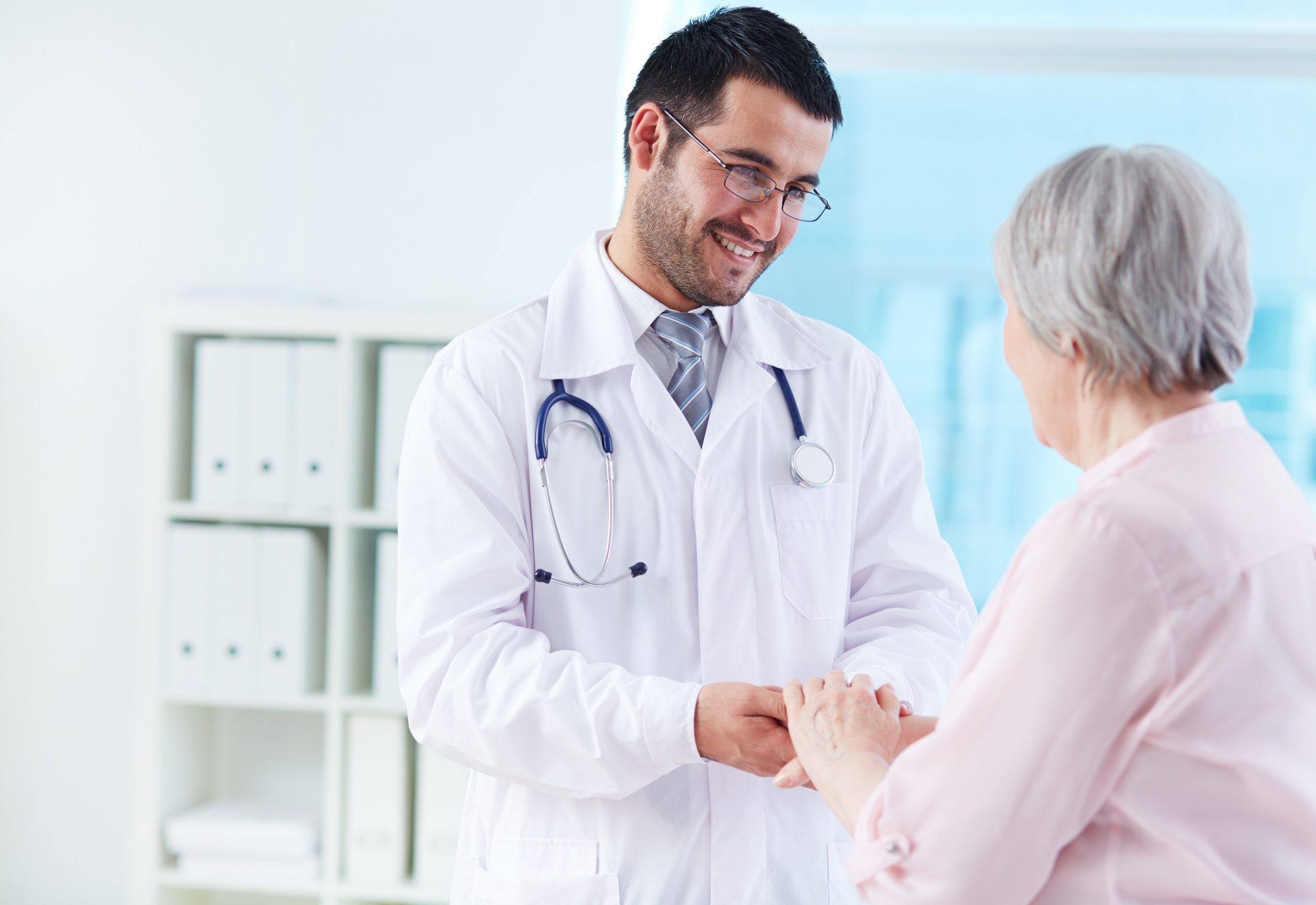 Médico sorrindo e conversando com paciente idosa em ambiente hospitalar